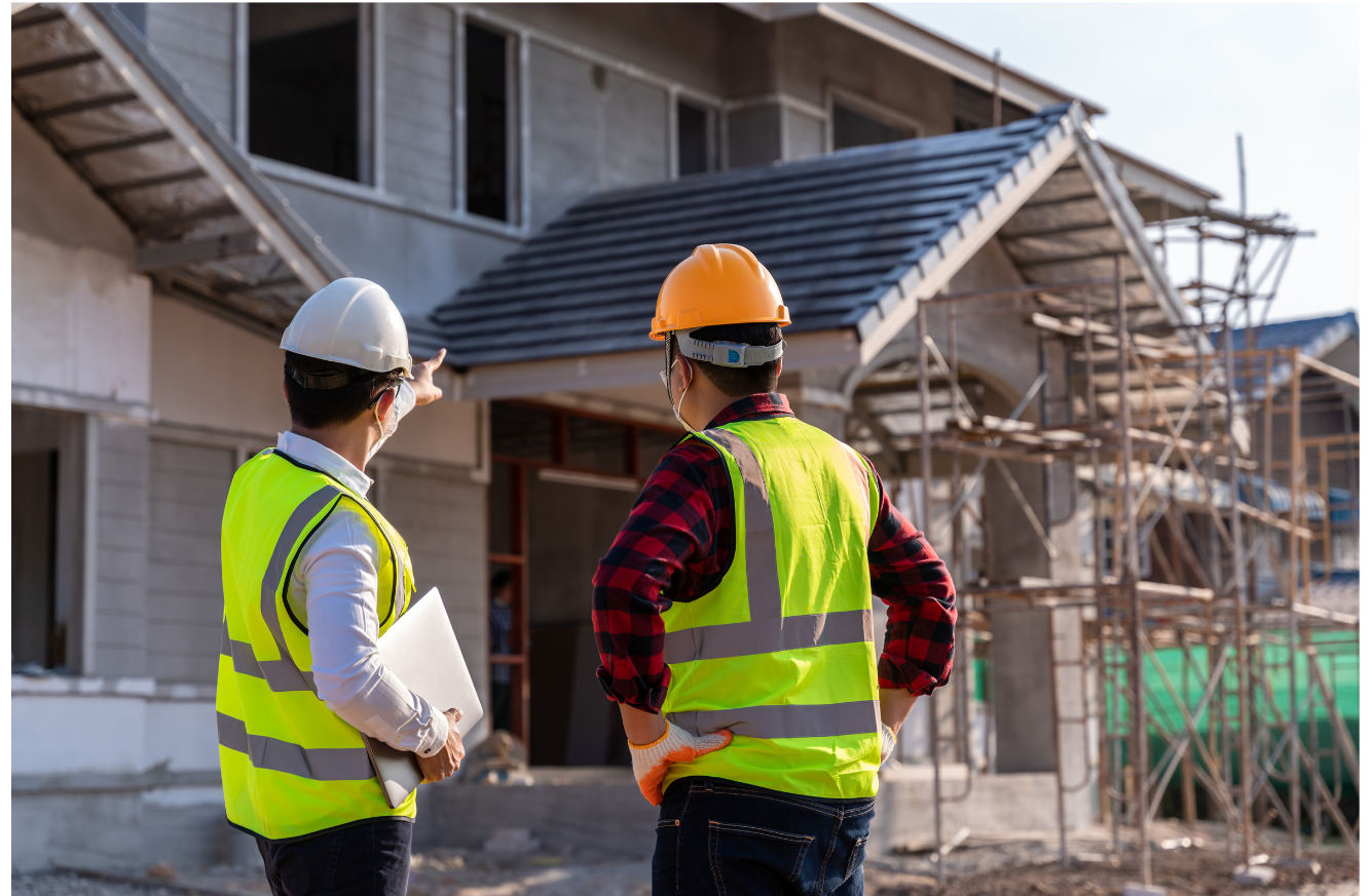 Construction Workers Inspecting Building Site Two construction workers with safety vests and hard hats inspecting a building under construction.