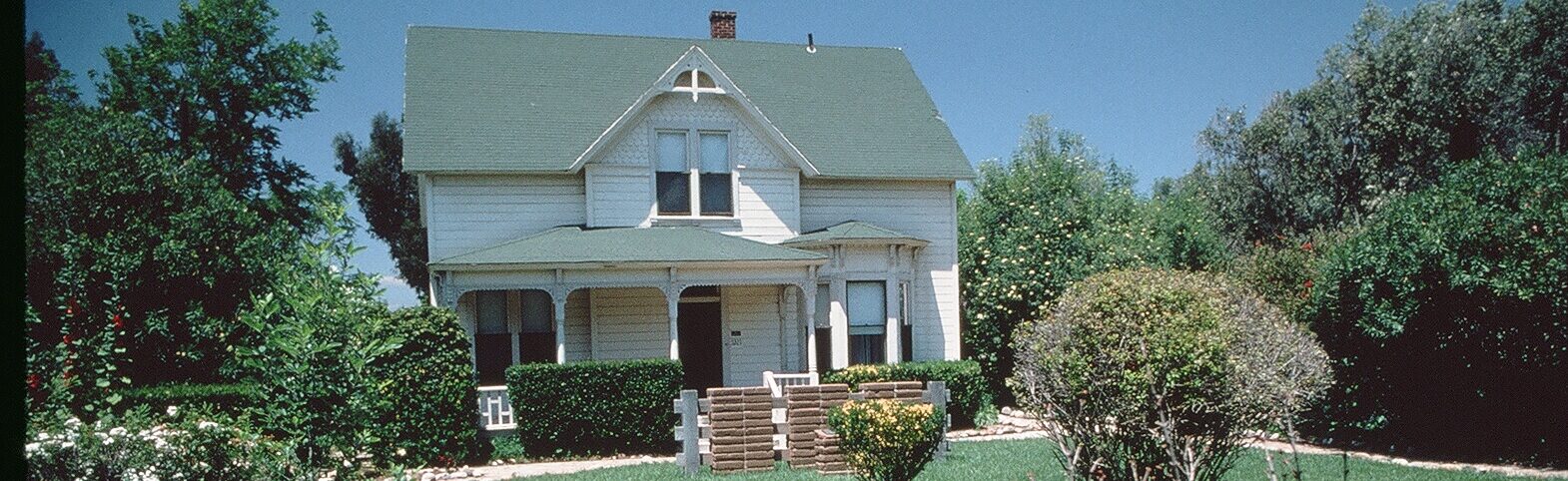 Victorian-style Strathearn home with a green roof, large porch, manicured lawn, and surrounding bushes, 1978.