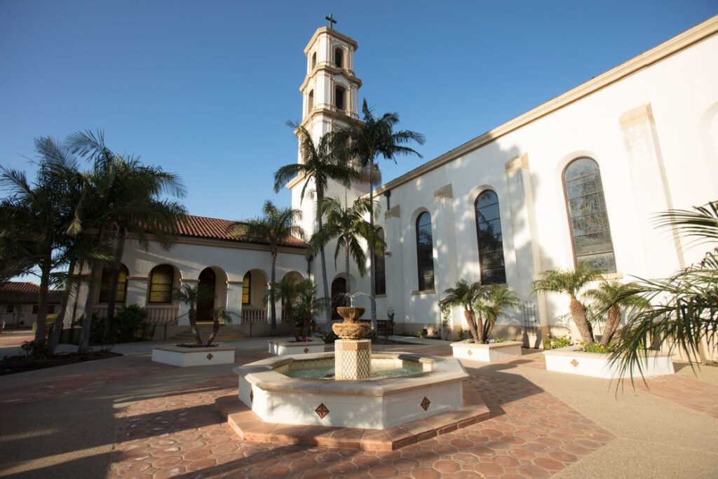 Courtyard of St. Mary Magdalen Church featuring a central fountain and palm trees.