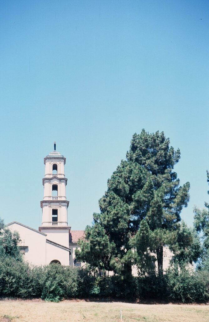 Exterior view of St. Mary Magdalen Church with a bell tower surrounded by greenery, 1978.
