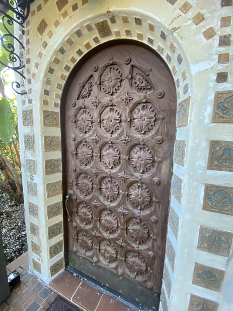 Ornately carved wooden door with decorative tiles arching the entrance.