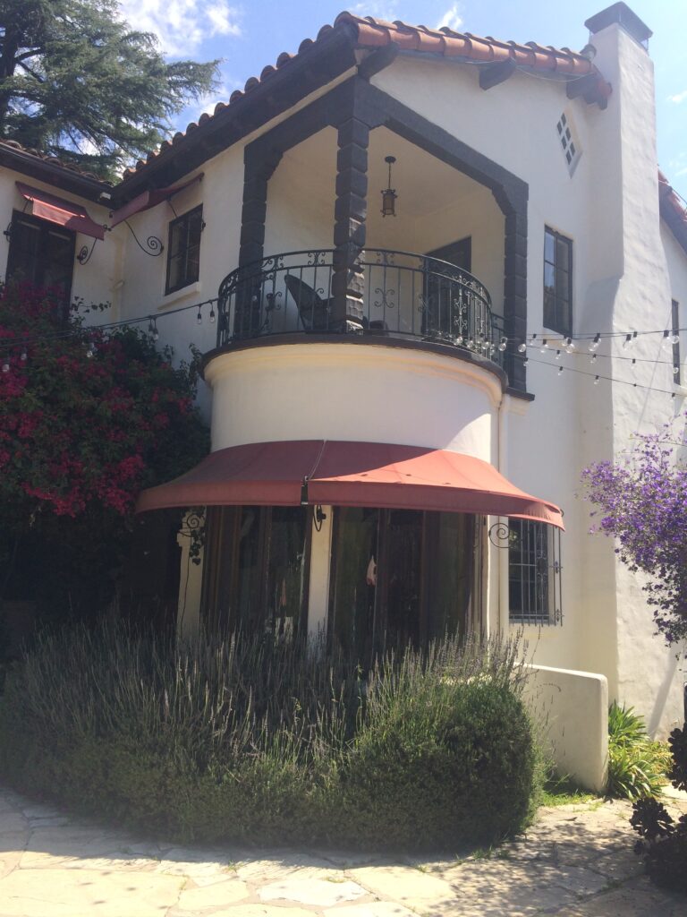 View of rear balcony with red awning and greenery.